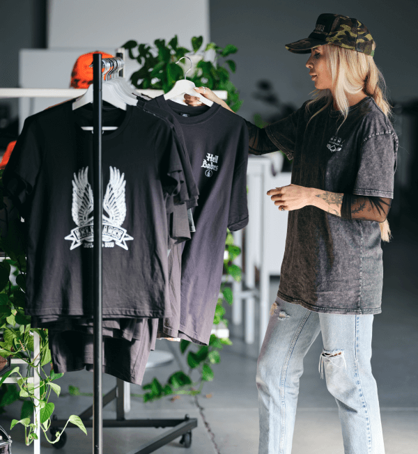 Photo of Hell Babes CEO Jessica Wise sorting through a rack of tee shirts in her store